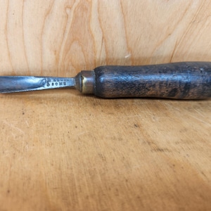 May include: A vintage wood handled chisel with a metal blade. The blade is marked "J. ROWEN & SONS".