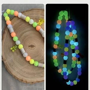 May include: A beaded necklace featuring round neon yellow, orange, and matte grey beads with small translucent yellow bear charms. The text Glow in the Dark appears at the top, and the beads emit a bright blue, green, and purple glow in the dark.