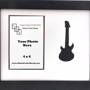 May include: Black picture frame with a white mat and a 4x6 inch opening. The mat has a cutout of a guitar and text that reads "Unique Frames For the Home Photo Frame Ready Your Photo Here 4 x 6 www.PhotoFrameReady.net"