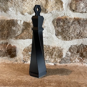 Könnte beinhalten: Ein schwarzer, geometrisch geformter Flaschenverschluss mit sechseckiger Oberseite.