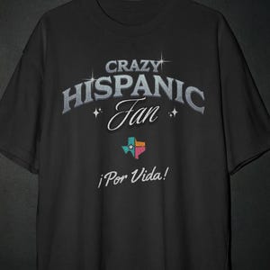 May include: Black t-shirt with the text "CRAZY HISPANIC Fan" in silver lettering. Below the text is a colorful graphic of the state of Texas and the phrase "¡Por Vida!" in white.