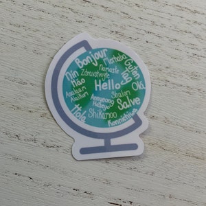 May include: A blue and green globe sticker with the word "Hello" in the centre and various greetings in different languages surrounding it.