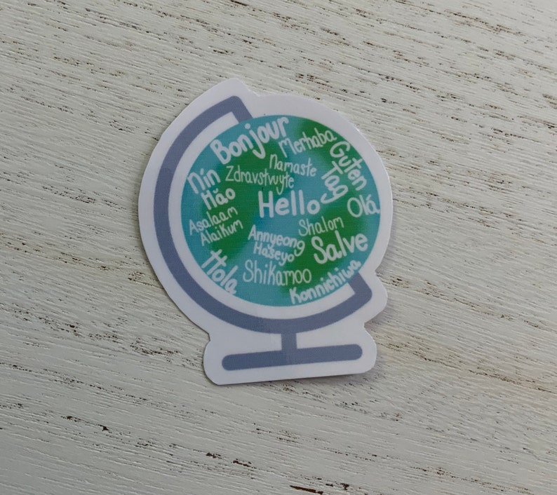 May include: A blue and green globe sticker with the word "Hello" in the centre and various greetings in different languages surrounding it.