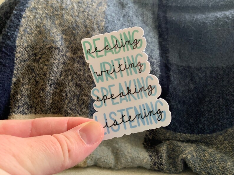 May include: A white sticker with the words "reading", "writing", "speaking", and "listening" in a stacked format. The words are written in a cursive font and are in shades of blue and green.