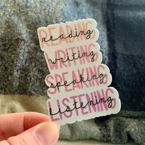 May include: A white sticker with the words "reading", "writing", "speaking", and "listening" in pink and black lettering.