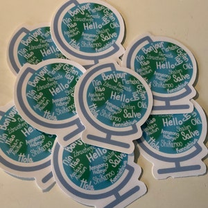 May include: A stack of blue and green globe stickers with the word "Hello" in multiple languages. The stickers are printed with a blue and green globe design and the words are arranged in a circle around the globe.