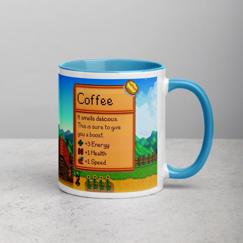 May include: A white coffee mug with a blue rim and handle. The mug features a pixelated image of a coffee bean with the text "Coffee" and a description of its effects: "It smells delicious. This is sure to give you a boost. +3 Energy +1 Health +1 Speed".