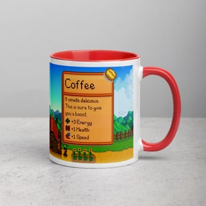 May include: White ceramic mug with a red rim and handle. The mug features a pixelated image of a coffee bean and a farm scene from the video game Stardew Valley. The text on the mug reads "Coffee" and "It smells delicious. This is sure to give you a boost. +3 Energy +1 Health +1 Speed."