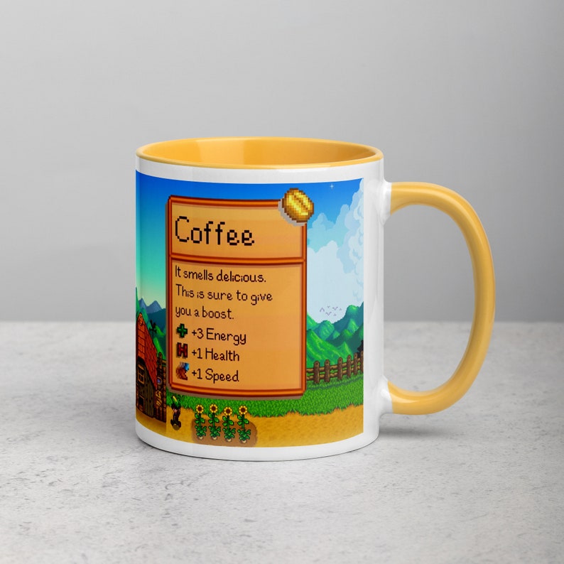 May include: A white coffee mug with a yellow rim and handle. The mug features a pixelated image of a video game character with the text "Coffee" and "It smells delicious. This is sure to give you a boost. +3 Energy +1 Health +1 Speed".