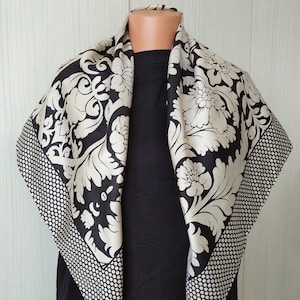 May include: A black and white silk scarf with a floral pattern. The scarf has a dotted border.