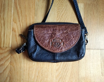May include: A black leather crossbody bag with a brown leather flap and a Harley Davidson logo. The bag has a zipper closure and a strap.