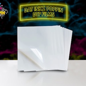 May include: A stack of white, clear, printable transfer sheets for use with a heat press. The sheets are on a white surface. The text "DAT INKZ POPPIN DTF FILMS" is in yellow neon letters on a black background.