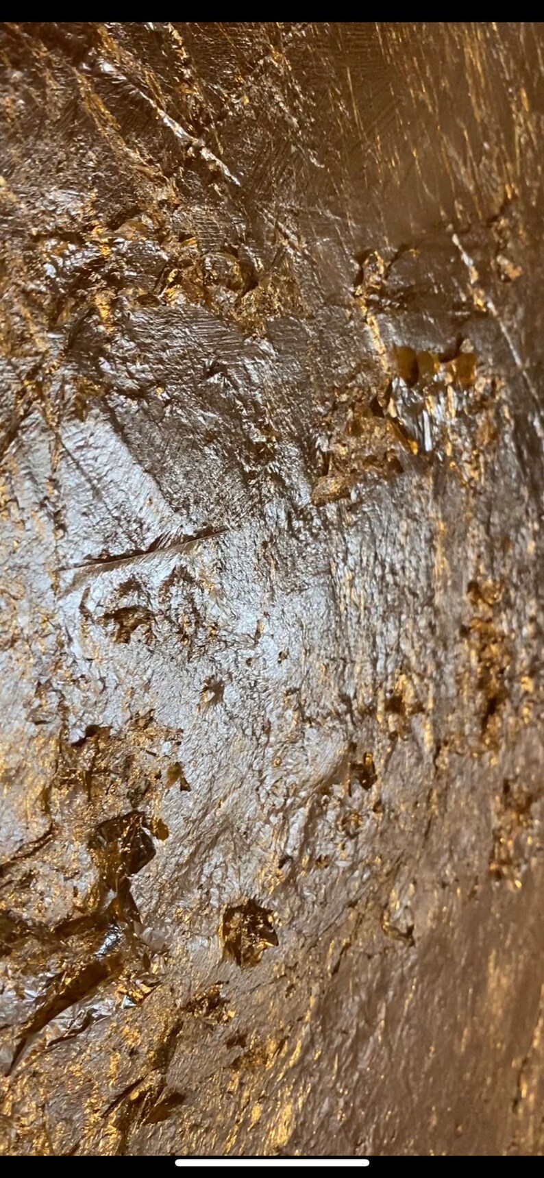 May include: Close-up of a textured gold surface with a metallic sheen. The surface has a rough, uneven texture with raised areas and crevices.
