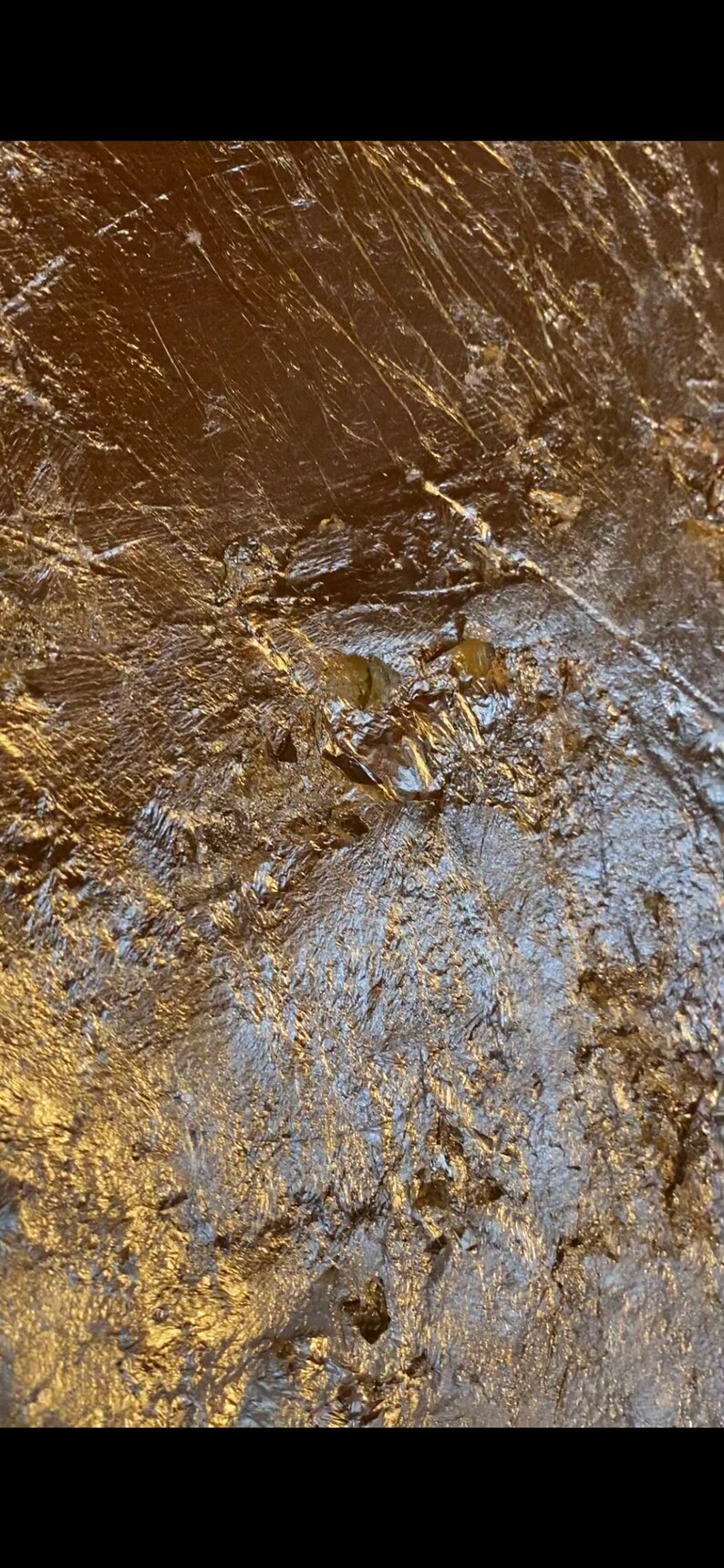 May include: Close-up of a textured, metallic surface with a gold finish. The surface has a wrinkled, crinkled appearance, creating a unique and abstract pattern.
