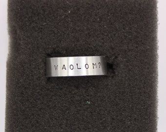 May include: A silver ring with the words "WAOLOM?" engraved on it.