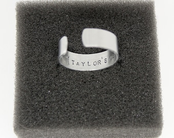 May include: A silver ring with the inscription "(TAYLOR'S" on the inside.