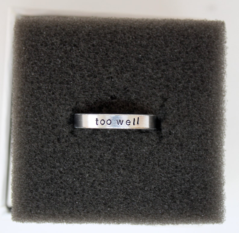 Puede incluir: Un anillo de plata con las palabras "too well" grabadas.
