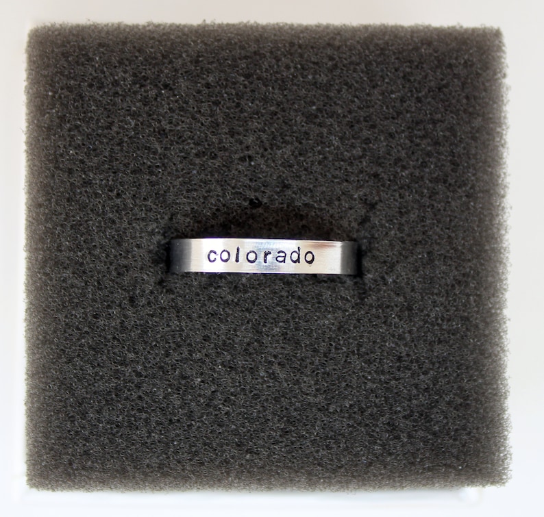 Puede incluir: Un anillo de plata con la palabra "colorado" grabada.