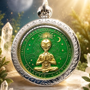 Könnte beinhalten: Ein runder silberner Anhänger mit einer goldfarbenen Alien-Figur in meditativer Haltung in der Mitte. Der Hintergrund ist grün mit einem geometrischen Muster, Sternen und einer Mondsichel. Der Text lautet AWAKENING ENERGY GALACTIC.