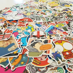 Könnte beinhalten: Eine große Sammlung bunter Aufkleber mit verschiedenen Comicfiguren, Logos und Designs. Die Aufkleber sind in einem zufälligen Muster angeordnet und beinhalten Bilder eines Schädels, einer Comicfigur, die einen Hotdog isst, und einer Comicfigur mit einem Blitz auf der Brust.