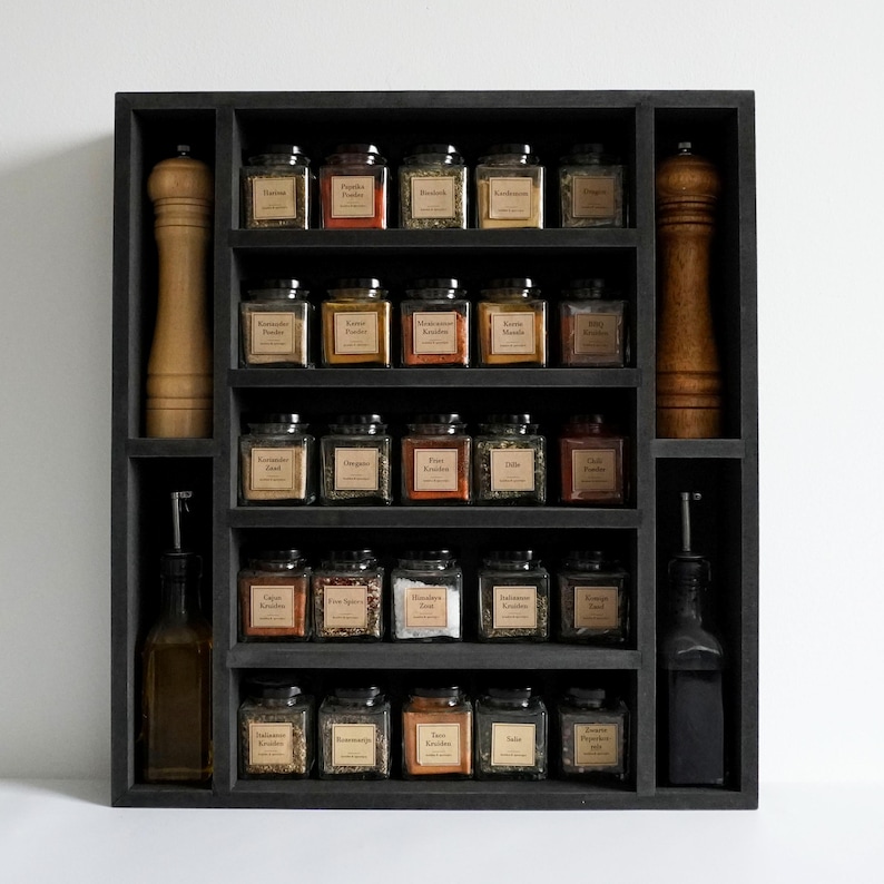 Może przedstawiać: Czarna drewniana p&oacute;łka na przyprawy z pięcioma p&oacute;łkami, każda z małymi szklanymi słoikami z etykietami. Słoiki są wypełnione r&oacute;żnymi przyprawami, w tym papryką, oregano i cynamonem. P&oacute;łka ma r&oacute;wnież dwa otwory na większe butelki, po jednej z każdej strony.