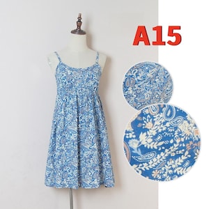 May include: A blue paisley print sundress with spaghetti straps, displayed on a mannequin. The dress features a gathered bodice and a flared skirt. The text "A15" is in the upper right corner. Two circular close-ups show the fabric pattern.