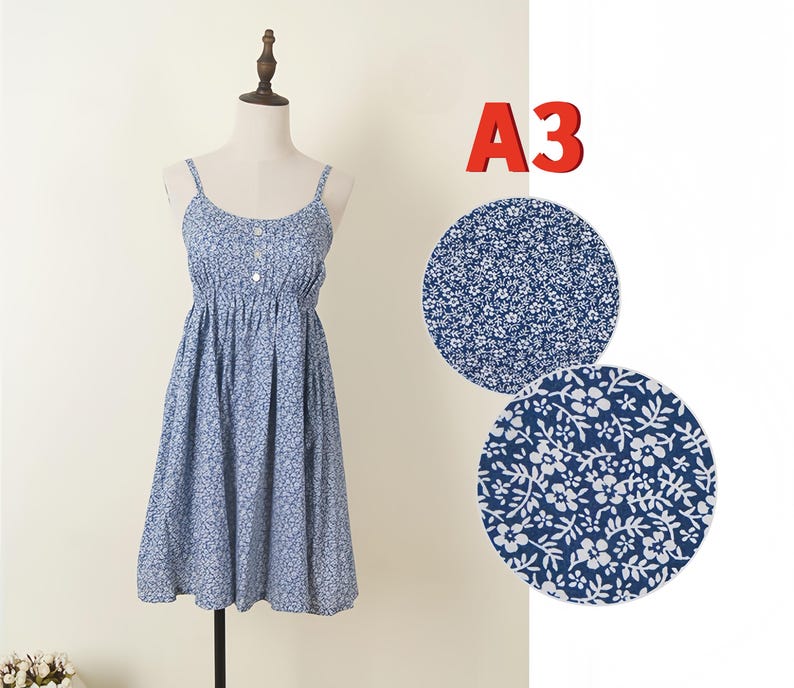 May include: A blue floral print sundress with spaghetti straps and a button-down front. The dress is displayed on a mannequin. Two fabric swatches with the same floral pattern are shown to the right, and the text "A3" is in the upper right corner.