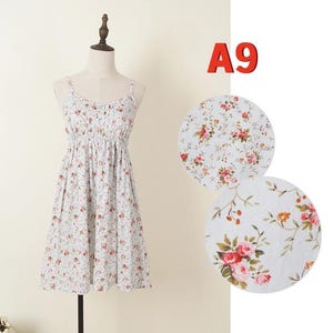 May include: A light blue floral print dress with spaghetti straps and a gathered waist. The dress is displayed on a mannequin. The fabric features a pattern of small red and pink flowers. The text "A9" is in the upper right corner.
