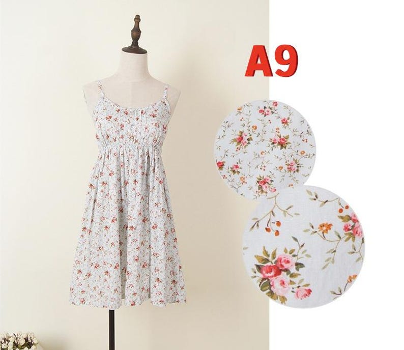 May include: A light blue floral print dress with spaghetti straps and a gathered waist. The dress is displayed on a mannequin. The fabric features a pattern of small red and pink flowers. The text "A9" is in the upper right corner.