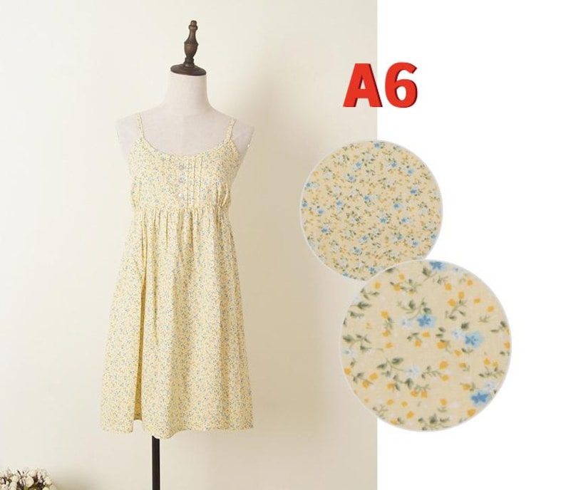 May include: A light yellow sundress with a floral pattern of small blue and yellow flowers. The dress has thin straps and a pleated bodice. The text "A6" is in red in the upper right corner. Two circular fabric swatches show the floral pattern.