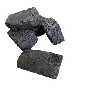 May include: A collection of irregularly shaped, dark gray bricks. The bricks have a rough, textured surface and are arranged in a loose pile against a white background. The overall appearance suggests a raw, industrial aesthetic.