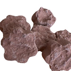 May include: A collection of reddish-brown, irregularly shaped rocks. The rocks have a rough, textured surface and vary in size. The image is set against a plain white background, highlighting the natural color and form of the stones.