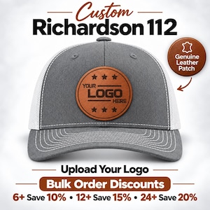 May include: A grey and white trucker hat featuring a circular brown leather patch on the front. The patch is embossed with the text YOUR LOGO HERE and six stars. The hat has a structured crown, a curved brim with white stitching, and mesh back panels.