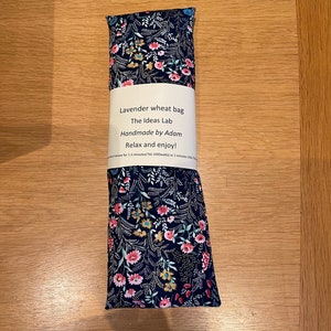 Pode incluir: Um saco de trigo de lavanda com estampa floral. O saco est&aacute; etiquetado "Lavender wheat bag, The Ideas Lab, Handmade by Adam, Relax and enjoy!"