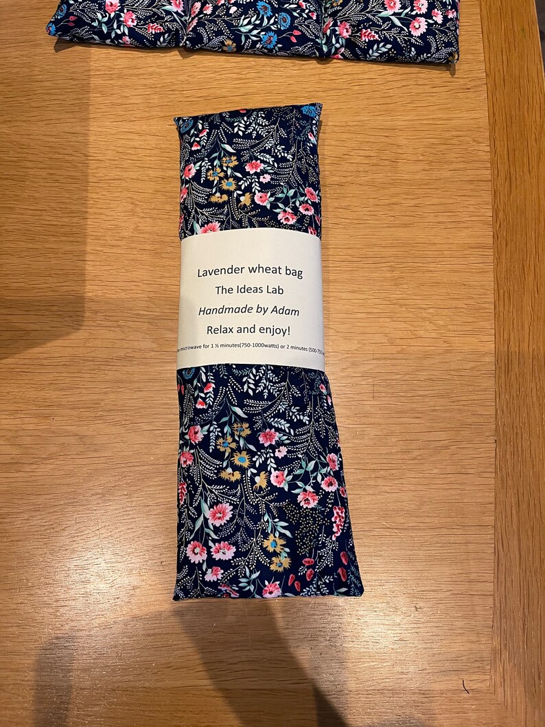 Pode incluir: Um saco de trigo de lavanda com estampa floral. O saco est&aacute; etiquetado "Lavender wheat bag, The Ideas Lab, Handmade by Adam, Relax and enjoy!"