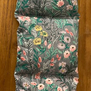 Pode incluir: Tr&ecirc;s almofadas de tecido cinzento com um padr&atilde;o floral. As almofadas t&ecirc;m um fundo cinzento claro com flores cor-de-rosa, amarelas e verdes.