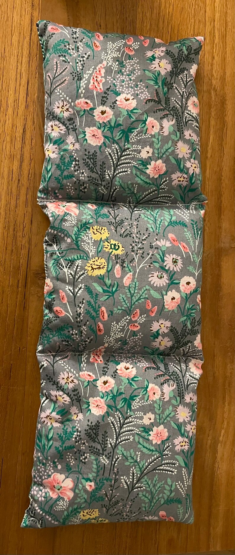 Pode incluir: Tr&ecirc;s almofadas de tecido cinzento com um padr&atilde;o floral. As almofadas t&ecirc;m um fundo cinzento claro com flores cor-de-rosa, amarelas e verdes.