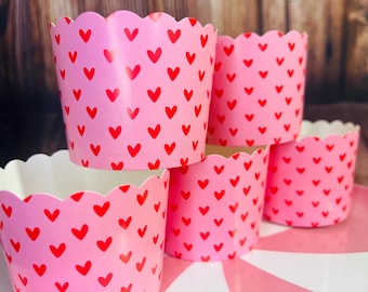 May include: Pink cupcake liners with a red heart pattern. The liners are stacked on top of each other.
