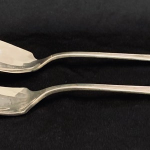 May include: A set of two silver-plated utensils, a fork and a spoon, with ornate designs on the handles.