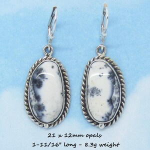 May include: Silver dangle earrings with white and black dendritic opal stones. The stones are oval shaped and set in a rope-like silver bezel. The earrings are 1-11/16" long and weigh 8.3g. 21 x 12mm opals.