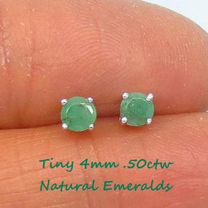 May include: A pair of tiny emerald earrings, each with a 4mm round green stone set in silver. The earrings are labeled "Tiny 4mm .50ctw Natural Emeralds".