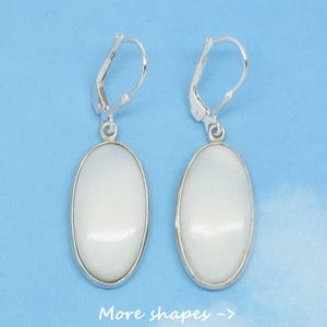 May include: A pair of silver earrings with white oval-shaped stones. The earrings have a lever back closure.