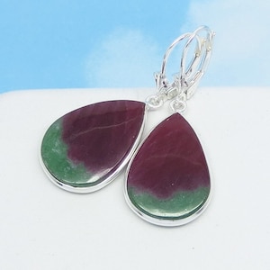 May include: A pair of silver dangle earrings with teardrop-shaped green and red gemstones.