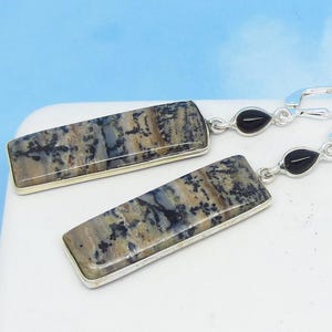 May include: A pair of silver dangle earrings with rectangular, multi-colored agate stones and black onyx accents.