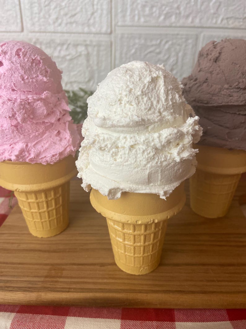 Pu&ograve; includere: Tre coni gelato decorativi con palline testurizzate nei colori rosa, bianco e marrone. Ogni pallina poggia su un cono beige con motivo a cialda. Le palline hanno un aspetto denso e montato con punte e creste visibili, che imitano il gelato vero.
