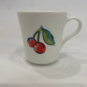 May include: White ceramic mug with a red and green cherry design.