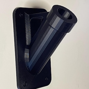 May include: Black plastic wall mount with a round opening for a flagpole. The mount has a rectangular base and a curved arm.