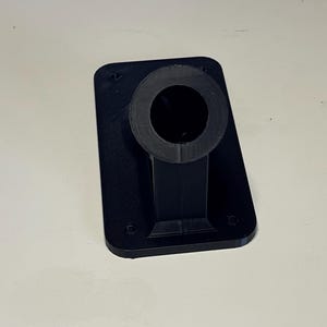 May include: A black plastic 3D printed wall mount with a round hole in the center.