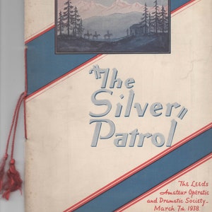 May include: A program cover for a play called "The Silver Patrol" by the Leeds Amateur Operatic and Dramatic Society. The cover features a blue and red striped background with a mountain scene and a small cabin. The date of the play is March 7th, 1938.