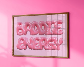 Può includere: Una stampa incorniciata con il testo "BADDIE ENERGY" in lettere 3D rosa su sfondo bianco.
